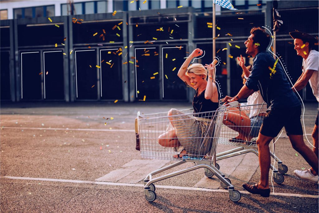 Konfetti fällt auf fröhliche Menschen bei Einkaufswagen-Rennen | eggheads.net