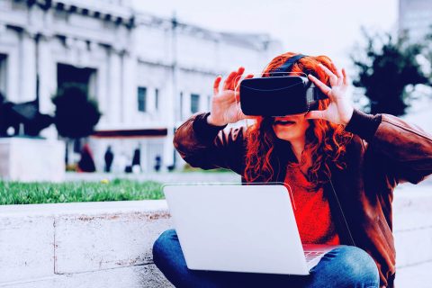 Woman sits cross-legged in garden and puts on VR headset | eggheads.net